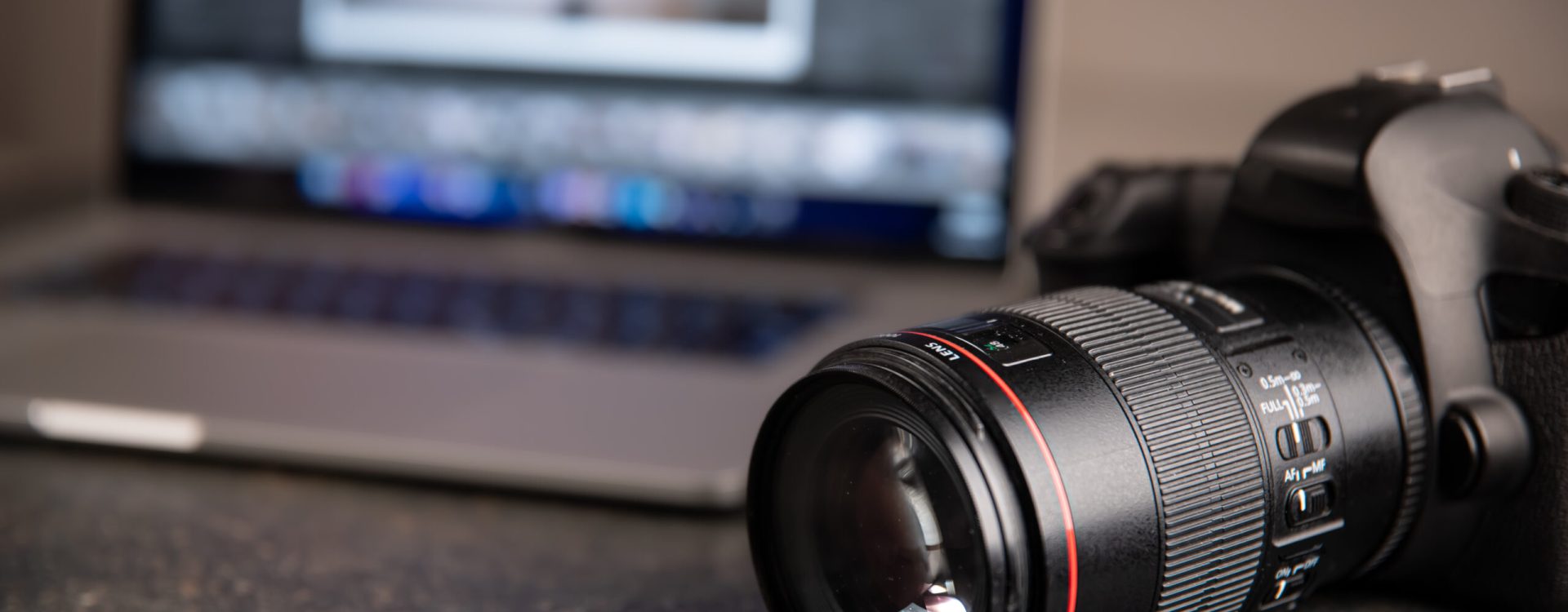 Professional camera on a blurred background with a laptop. The concept of working with photos and videos.